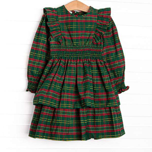  This dress features a green plaid print, ruffle trim, and elastic smocking. 