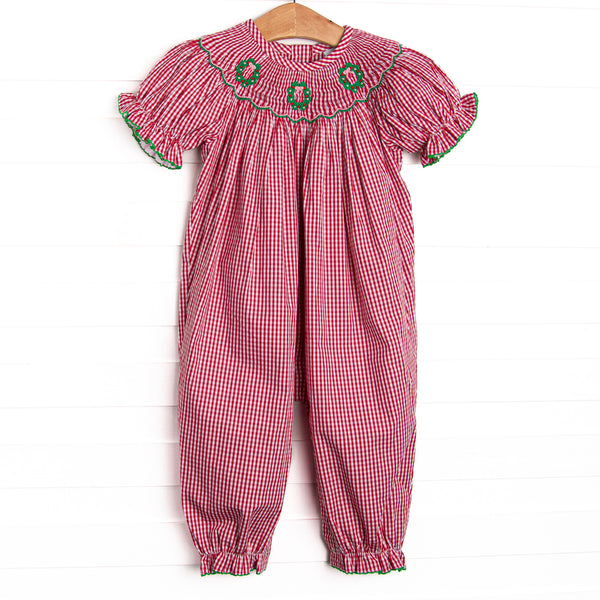 his romper features a red gingham print, puff sleeves, and a trio of wreath smockings.