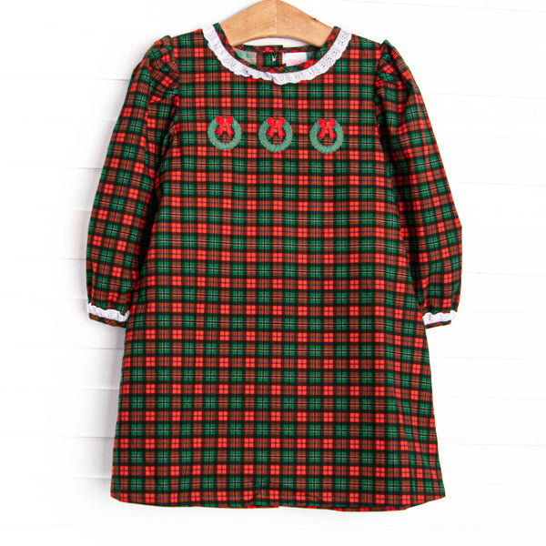  This dress features a red plaid print, white ruffles, and a trio of wreath embroideries. 