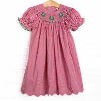 This dress features a red gingham print, puff sleeves, and a trio of wreath smockings.
