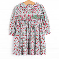 This dress features a red and green floral print, ruffle collar, and a dainty geometric smocking.