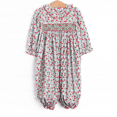 This romper features a red and green floral print, ruffle collar, and a dainty geometric smocking