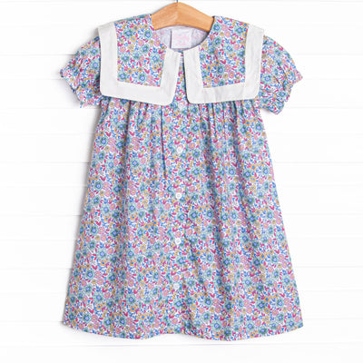 This dress features a purple floral print, a bib collar, and puff sleeves.