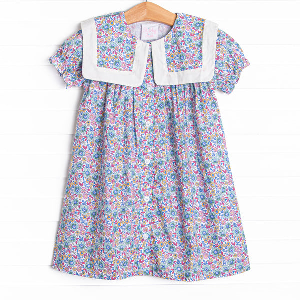 This dress features a purple floral print, a bib collar, and puff sleeves.