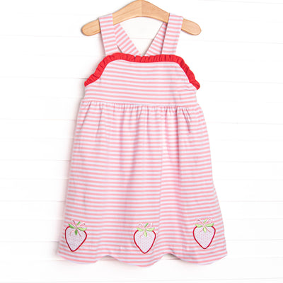 This dress features a pink striped print, red ruffle trim, and a trio of strawberries appliques.