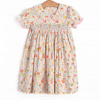 This dress features a pink floral print, puff sleeves, a dainty smocking.