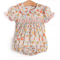 This bubble features a pink floral print, puff sleeves, a dainty smocking.