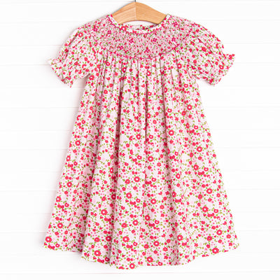 This dress features a pink floral print, buttons on the back, and a floral smocking.