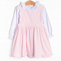  This set features a long sleeve top with a ruffle collar and a pink corduroy jumper with a scalloped edge. 