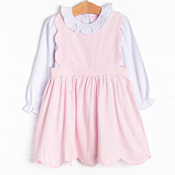  This set features a long sleeve top with a ruffle collar and a pink corduroy jumper with a scalloped edge. 