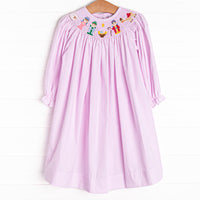 The dress features in pink gingham boasts adorable long puff sleeves and a smocked Christmas scene.