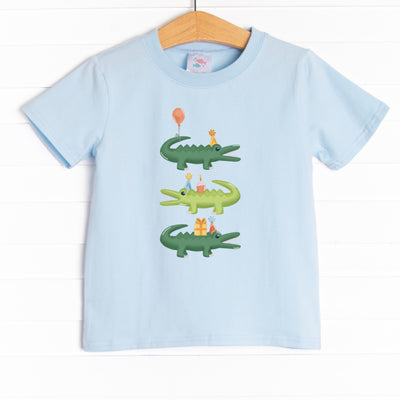  The shirt is featured in four colors; White, Heather Gray, Ballerina Pink, and Soft Blue with a crocodile birthday graphic. 