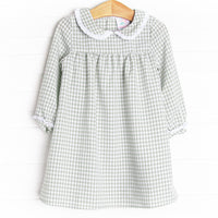 This dress is featured in a green gingham print, with a peter pan collar with a ruffle detail.