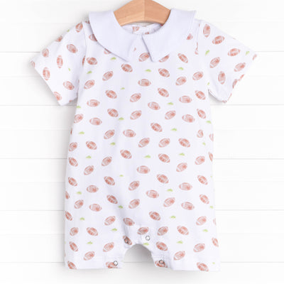  The romper features a Peter Pan collar, snaps at the stride to make changing a breeze, and a football filled print. 