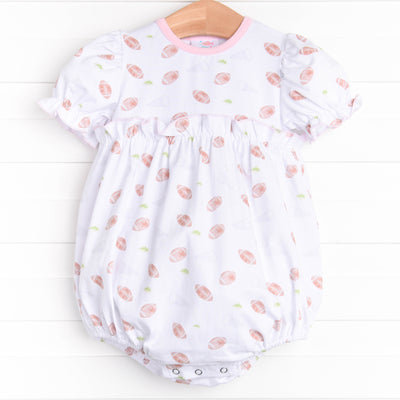  The&nbsp;bubble features short puff sleeves, snaps at the stride to make changing a breeze, and a football filled print. 